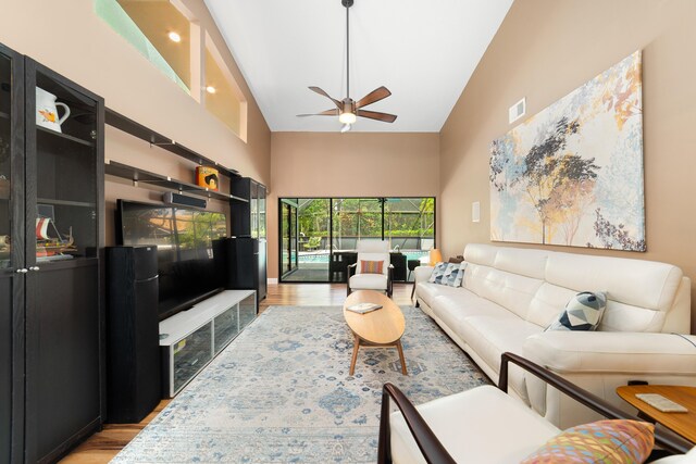 living area with visible vents, a ceiling fan, wood finished floors, and high vaulted ceiling