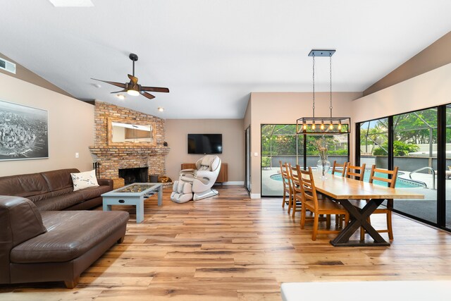 dining room with vaulted ceiling, a wealth of natural light, ceiling fan with notable chandelier, and light wood-type flooring
