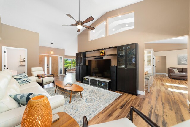 living area featuring light wood-type flooring, baseboards, ceiling fan, and high vaulted ceiling