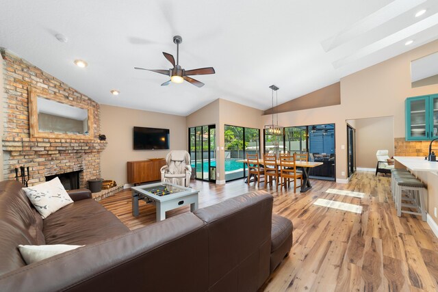 living room featuring a ceiling fan, baseboards, light wood-style flooring, and a fireplace