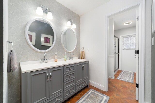 bathroom featuring double vanity, baseboards, wallpapered walls, and a sink