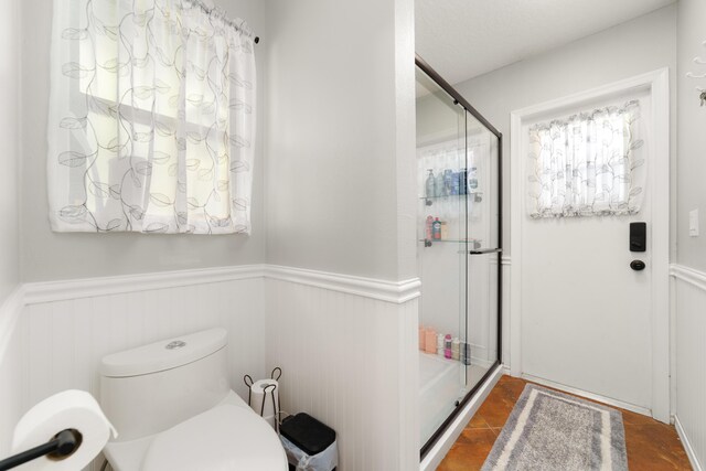 full bathroom featuring a wainscoted wall and a stall shower