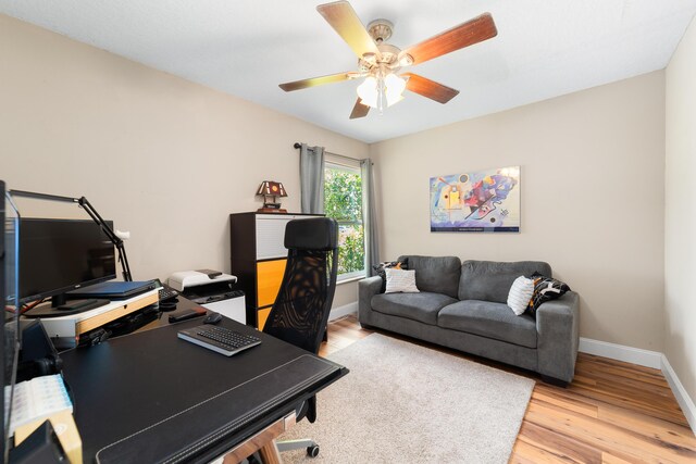 office space with a ceiling fan, baseboards, and light wood finished floors