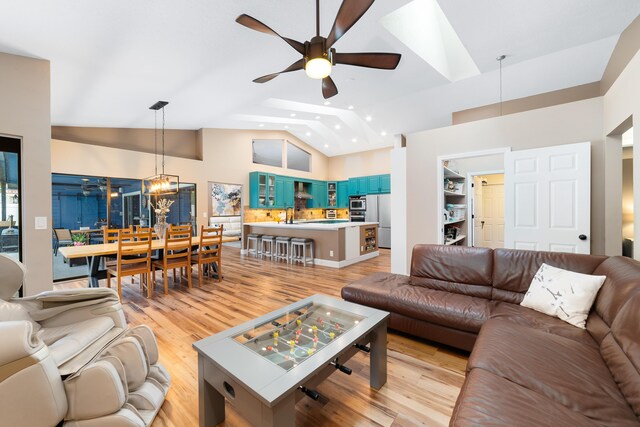 living room featuring recessed lighting, light wood-style flooring, ceiling fan with notable chandelier, and high vaulted ceiling