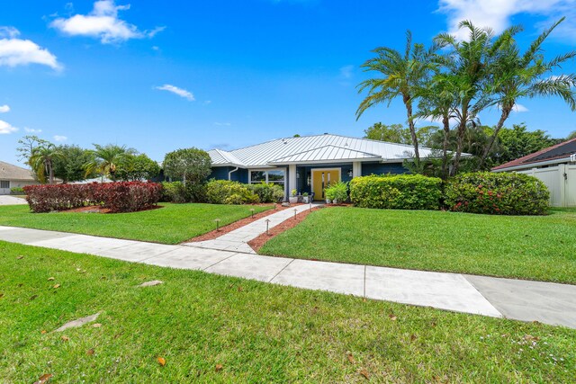 single story home with a standing seam roof, fence, metal roof, and a front yard