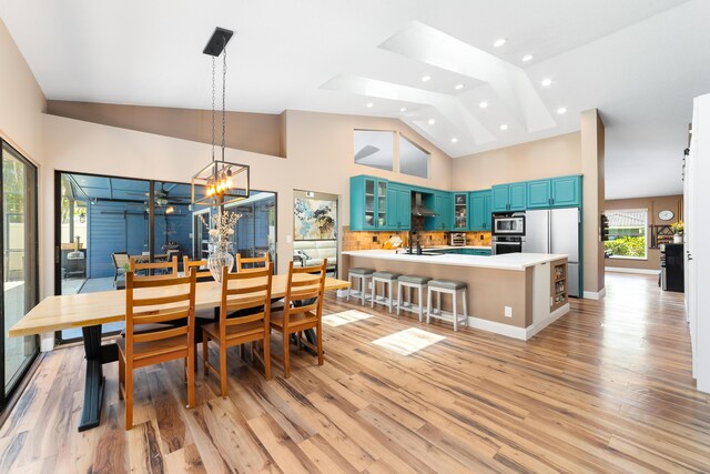 dining room with light wood-style floors, high vaulted ceiling, an inviting chandelier, and recessed lighting