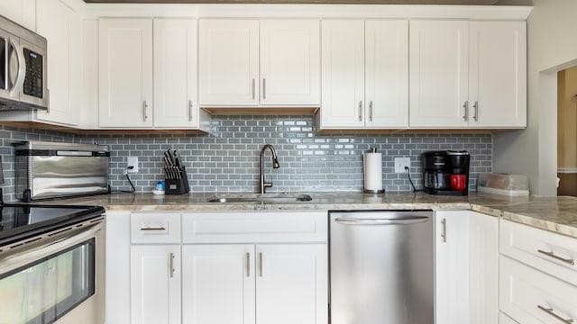kitchen featuring white cabinetry, stainless steel appliances, backsplash, and a sink