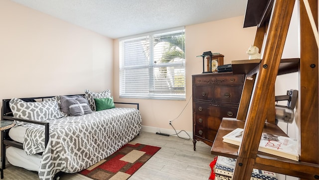 bedroom with a textured ceiling, wood finished floors, and baseboards