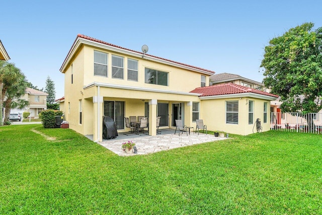 rear view of property with a tile roof, a lawn, a patio area, and stucco siding