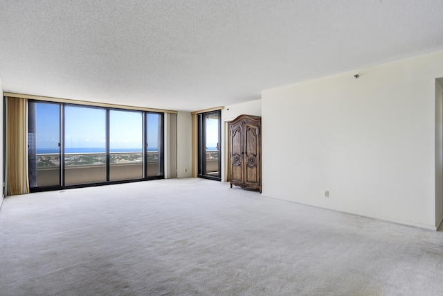 529 S Flagler Dr Unit 25F, West Palm Beach, FL 33401 - unfurnished living room with a wall of windows, light carpet, and a textured ceiling