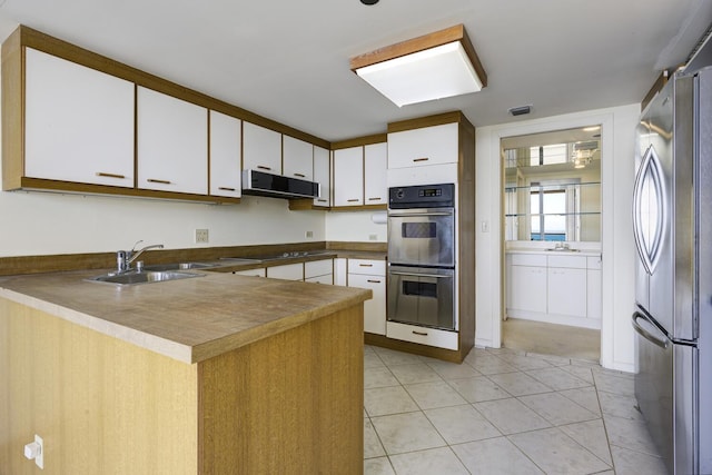 529 S Flagler Dr Unit 25F, West Palm Beach, FL 33401 - kitchen with a peninsula, white cabinetry, a sink, stainless steel appliances, and extractor fan