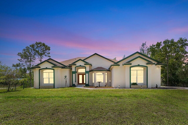 ranch-style house featuring french doors, a lawn, stucco siding, and fence