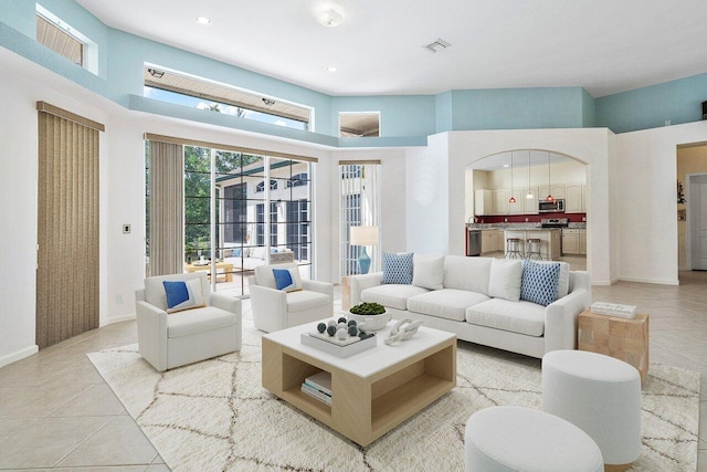 tiled living room with recessed lighting, visible vents, baseboards, and a high ceiling