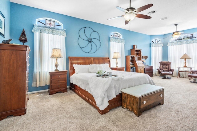 carpeted bedroom with a ceiling fan, visible vents, and multiple windows