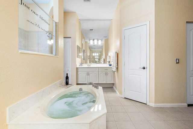 full bath featuring a garden tub, vanity, a textured wall, tile patterned flooring, and visible vents