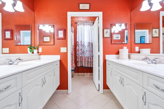 full bath with two vanities, a textured wall, a sink, and tile patterned floors