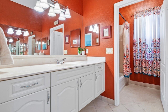 full bathroom with a textured wall, shower / bath combo with shower curtain, tile patterned flooring, and vanity