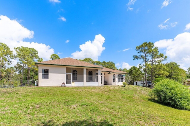 rear view of property with stucco siding, fence, and a yard