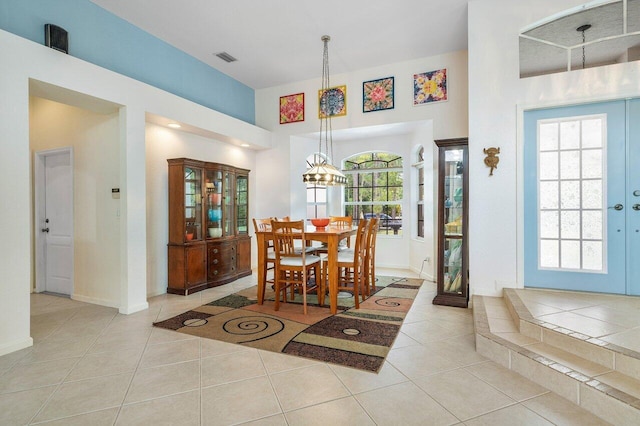 tiled dining area featuring baseboards, a healthy amount of sunlight, a chandelier, and visible vents