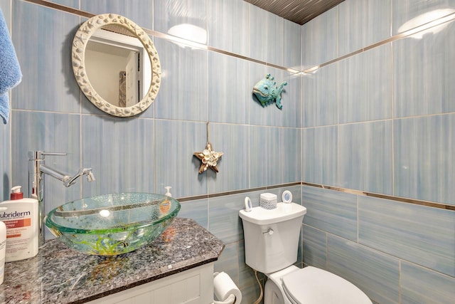 bathroom featuring toilet, vanity, and tile walls
