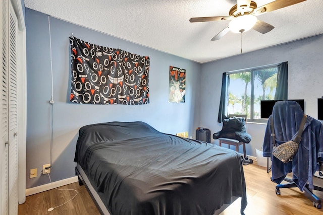 bedroom with a textured ceiling, wood finished floors, and ceiling fan