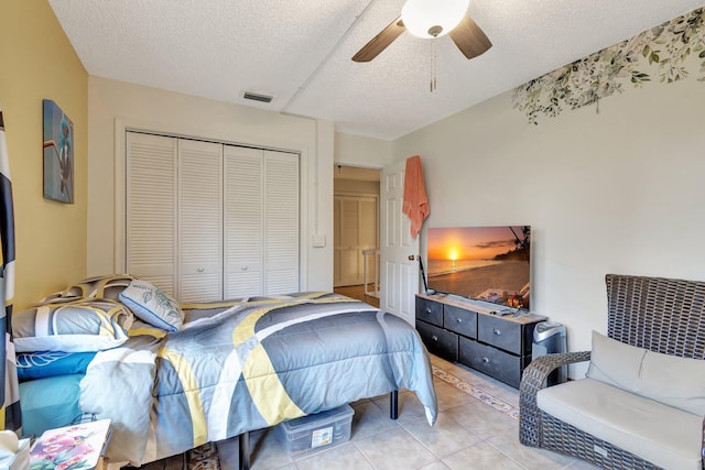 bedroom featuring ceiling fan, a textured ceiling, a closet, visible vents, and light tile patterned flooring