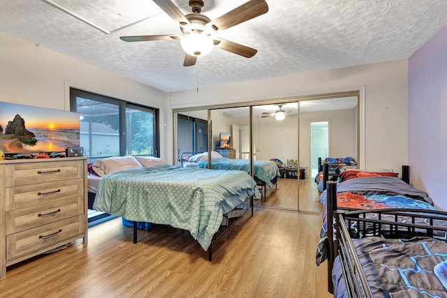 bedroom featuring a closet, light wood finished floors, a textured ceiling, and ceiling fan