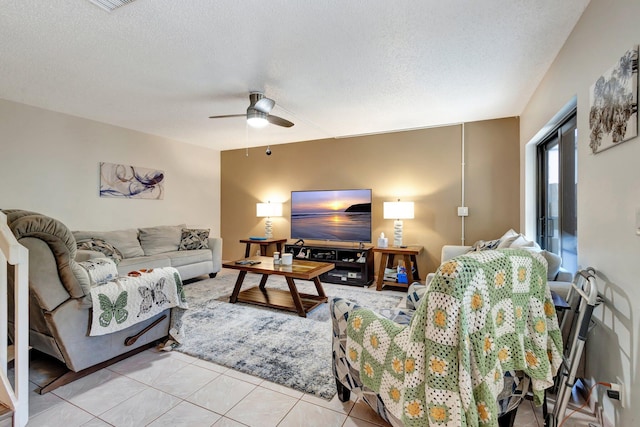 living area with light tile patterned floors, a ceiling fan, and a textured ceiling