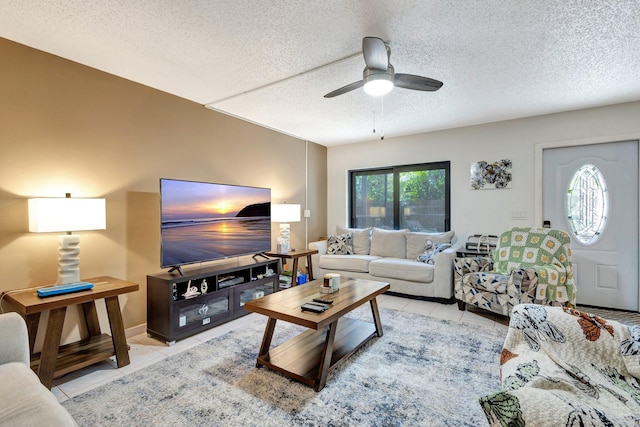 living area featuring ceiling fan, a textured ceiling, and light tile patterned flooring