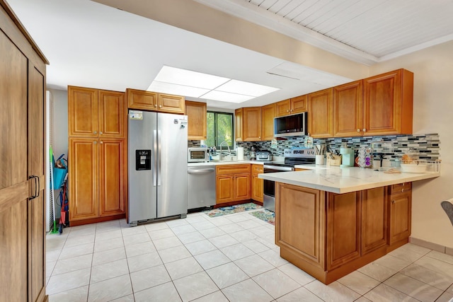 kitchen with a peninsula, decorative backsplash, light countertops, and stainless steel appliances