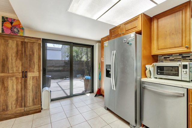 kitchen with light tile patterned floors, light countertops, appliances with stainless steel finishes, decorative backsplash, and a toaster