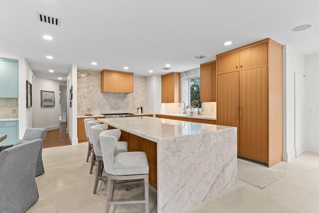 5 Osprey Ct, Ocean Ridge, FL 33435 - kitchen featuring tasteful backsplash, a kitchen island, light stone countertops, recessed lighting, and a breakfast bar area