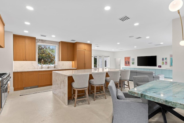 5 Osprey Ct, Ocean Ridge, FL 33435 - kitchen with a center island, a breakfast bar, stainless steel range, tasteful backsplash, and recessed lighting
