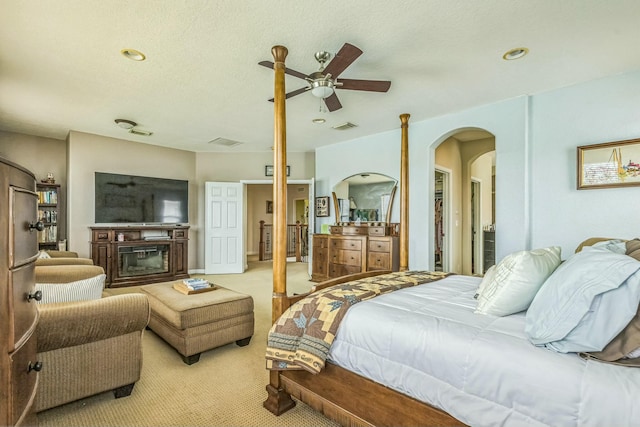 694 Cresta Cir, West Palm Beach, FL 33413 - bedroom with a ceiling fan, a glass covered fireplace, arched walkways, light carpet, and visible vents