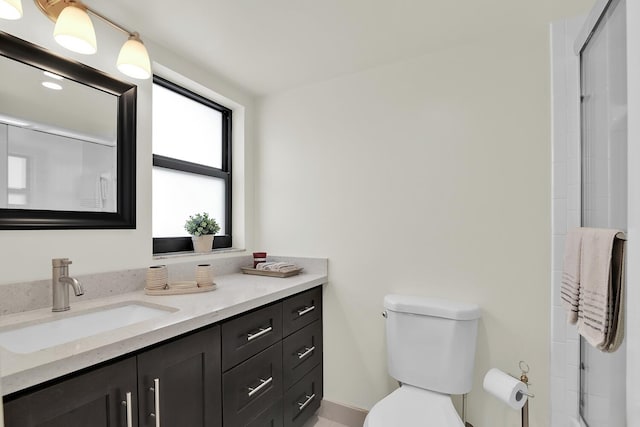 bathroom featuring toilet, a shower with door, and vanity