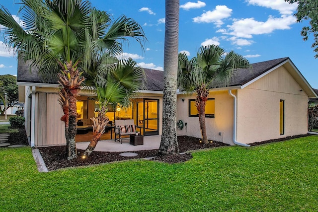 back of property with an outdoor living space, stucco siding, a yard, and a patio