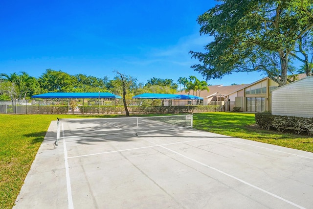view of community featuring fence, a yard, and a tennis court