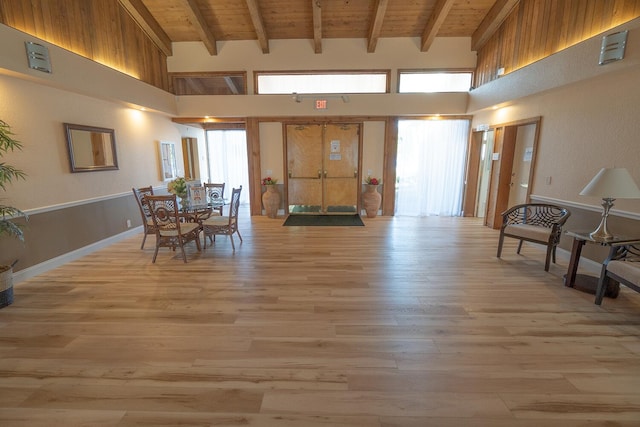 dining room featuring a high ceiling, wooden ceiling, beam ceiling, and light wood-type flooring