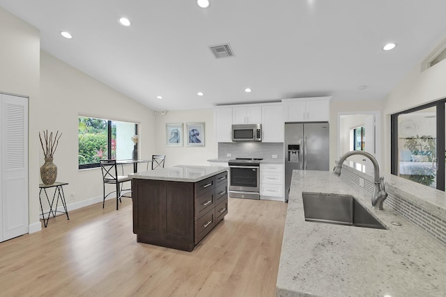 kitchen featuring a sink, stainless steel appliances, white cabinetry, a kitchen island, and visible vents