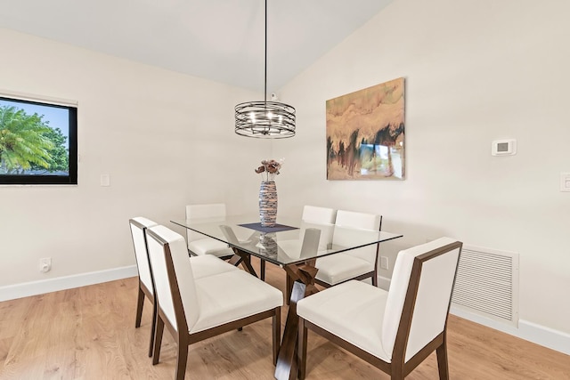 dining room featuring light wood-style floors, visible vents, vaulted ceiling, baseboards, and an inviting chandelier