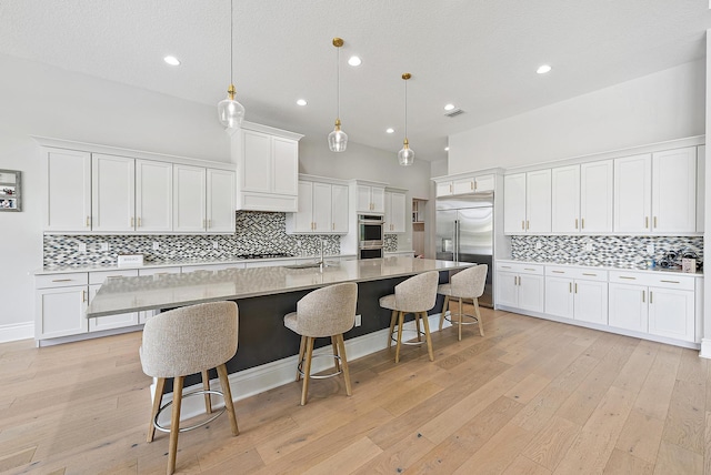 kitchen featuring white cabinets, tasteful backsplash, a breakfast bar, and appliances with stainless steel finishes