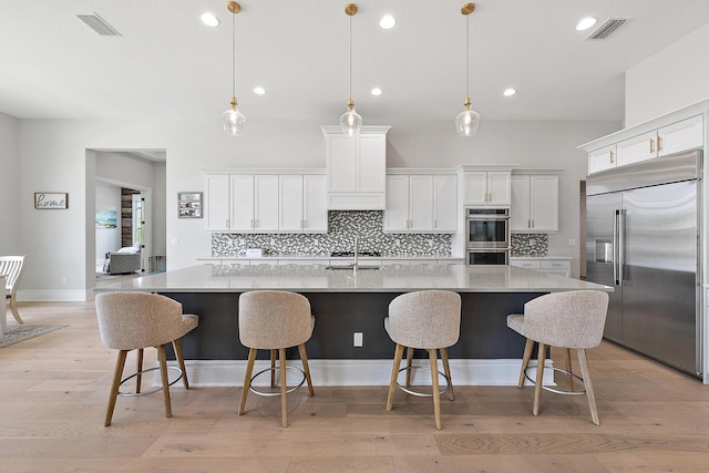 kitchen with tasteful backsplash, visible vents, appliances with stainless steel finishes, and white cabinetry