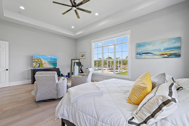 bedroom featuring baseboards, a raised ceiling, a ceiling fan, recessed lighting, and wood finished floors