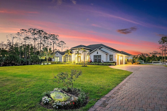 single story home featuring a front yard, a garage, fence, stucco siding, and decorative driveway