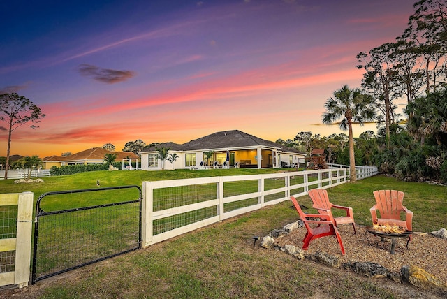 yard at dusk featuring a fire pit, fence, and a gate