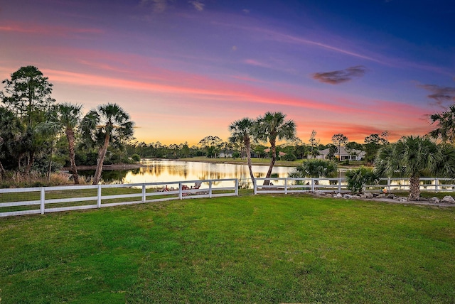 yard at dusk with fence and a water view