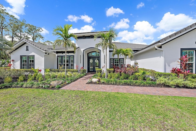 mediterranean / spanish-style house with french doors, stucco siding, and a front lawn
