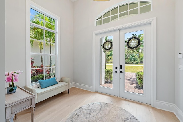 entryway with french doors, wood finished floors, and baseboards