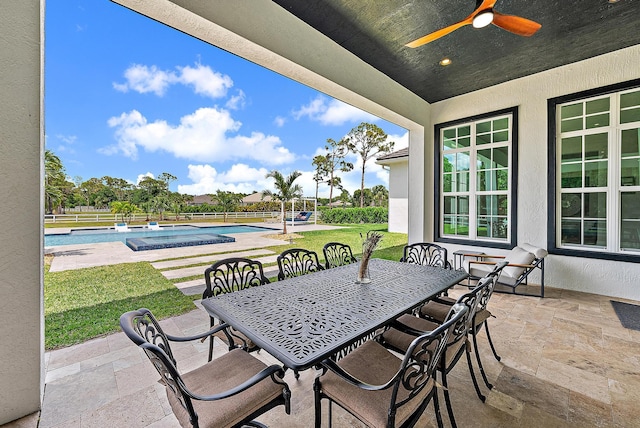 view of patio with outdoor dining space, ceiling fan, a fenced in pool, and fence