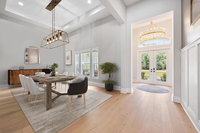 dining space featuring a chandelier, light wood-style floors, a high ceiling, and french doors